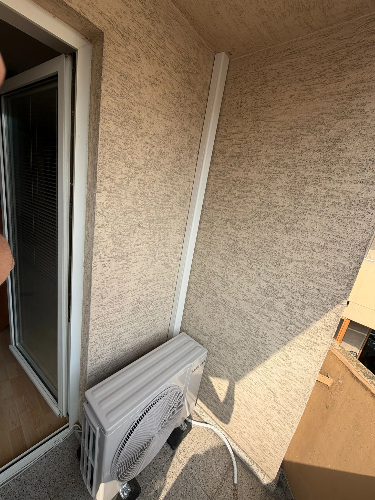 Zufriedener Kunde mit Klimaanlage im Wohnzimmer, Außengerät am Balkon von Klimadealer
